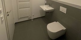Ein modernes Badezimmer mit einem weißen WC, einem Waschbecken und einem Handtuchheizkörper an der Wand.