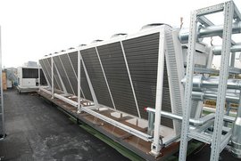 Auf dem Dach sind mehrere Kühlsysteme installiert, die in einer Reihe angeordnet sind und eine moderne Architektur zeigen.