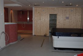 Ein eleganter Wellnessbereich mit einem Whirlpool und einer Sauna, umgeben von modernen Fliesen und Holzverkleidungen.
