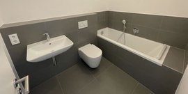 Das Badezimmer zeigt eine schlichte, zeitgemäße Gestaltung mit einer Badewanne, einem Waschbecken und einem modernen WC.