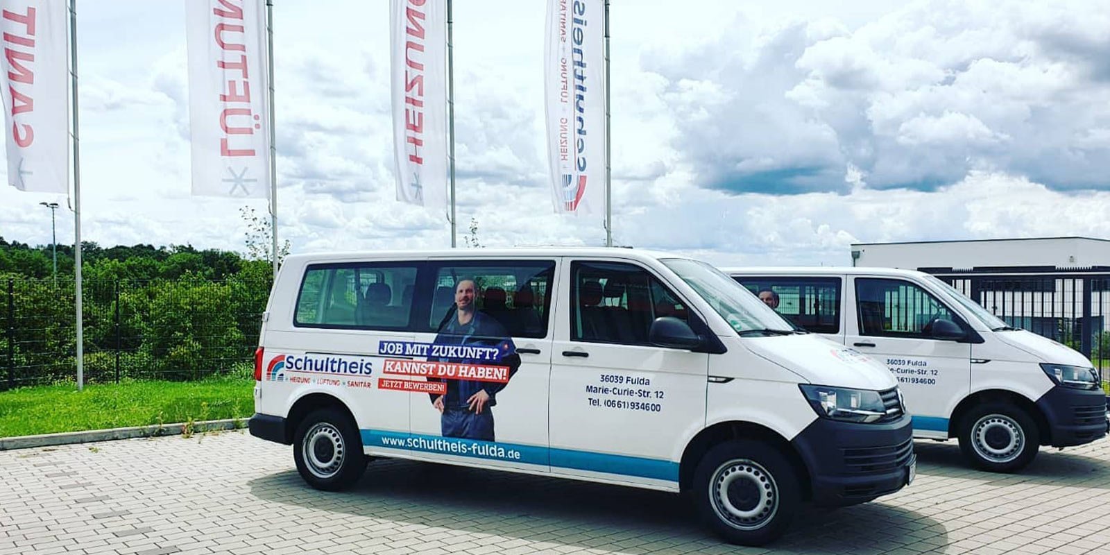 Die Fahrzeuge sind mit einem Aufruf zur Bewerbung für einen Job in der Nähe von Fulda versehen, umgeben von einer grünen Kulisse.