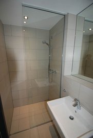 Eine moderne Dusche mit gläserner Trennwand und eleganten Fliesen, die ein Gefühl von Raum und Licht vermittelt.