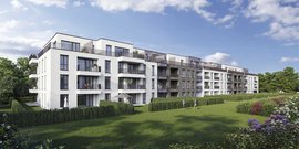 Moderne Wohnanlage mit mehreren Etagen, umgeben von gepflegten Gärten und bunten Blumenbeeten unter einem klaren Himmel.