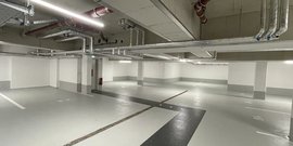 Der Innenraum eines Parkhauses mit sichtbaren Rohren an der Decke und einem sauberen, gut beleuchteten Bodenbereich.