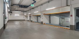 Der Innenraum eines Parkhauses zeigt eine saubere, geräumige Fläche mit einem Ausfahrtsschild und einem Notausgang.