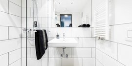 Das Badezimmer zeigt eine stilvolle Dusche mit Glasabtrennung, einem Handtuchhalter und Pflegeprodukten auf einem Regal.