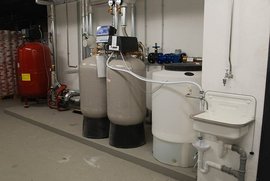Der Raum enthält mehrere Wasseraufbereitungsgeräte, darunter zwei große Filter und einen kleinen Waschbecken mit Abfluss.
