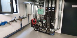 Ein technischer Raum mit Rohren, Ventilen und einem Steuergerät, das zur Überwachung von Wasser- oder Heizsystemen dient.