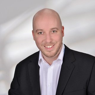 Professionelles Porträt eines lächelnden Mannes im Anzug Der Mann in formeller Kleidung strahlt Selbstbewusstsein aus, während er in die Kamera lächelt, umgeben von einem neutralen Hintergrund.