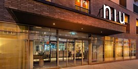 Der Eingangsbereich eines modernen Hotels mit großen Glasfenstern und einem stilvollen Empfangsbereich ist gut beleuchtet.