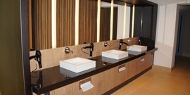 Ein modernes Badezimmer mit mehreren Waschbecken, eleganten Armaturen und stilvollen Holzverkleidungen an der Wand.