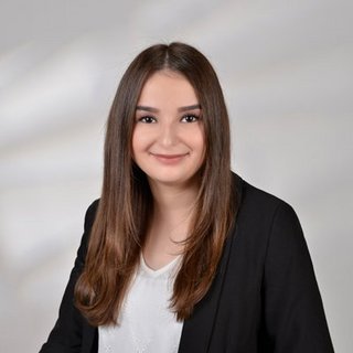 Professionelles Porträt einer jungen Frau im Anzug Eine junge Frau mit langen, glatten Haaren lächelt freundlich in die Kamera, gekleidet in einem schwarzen Blazer.