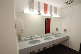 Ein modernes Badezimmer mit drei Waschbecken, einem großen Spiegel und stilvollen Wänden in neutralen Farben.