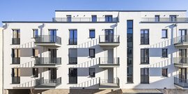 Ein zeitgenössisches Wohnhaus mit mehreren Etagen, das durch seine hellen Farben und architektonische Klarheit besticht.