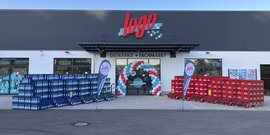 Vor dem Getränkemarkt stehen hohe Stapel von blauen und roten Getränkekisten, die eine einladende Atmosphäre schaffen.