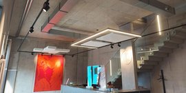 Ein modernes Empfangsbereich mit Betonwänden, einer auffälligen roten Wandkunst und stilvollen Deckenleuchten.