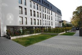 Die Architektur des Gebäudes zeigt eine Kombination aus weißen Wänden und einem dunklen Dach, ergänzt durch einen kleinen Garten.