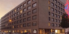 Ein modernes Gebäude mit vielen Fenstern, das in der Dämmerung beleuchtet ist, vermittelt eine einladende Atmosphäre.