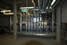 Ein komplexes Rohrleitungssystem mit zahlreichen Ventilen und Messgeräten in einem industriellen Raum.