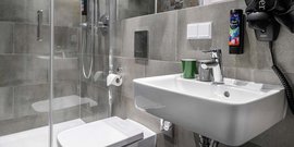 Ein modernes Badezimmer mit einer Dusche, einem Waschbecken und einem WC, alles in eleganten Grautönen gestaltet.