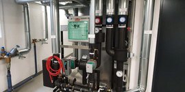 Eine komplexe Anordnung von Rohren und Ventilen in einem technischen Raum, die für Heizungs- oder Kühlungsanlagen genutzt wird.