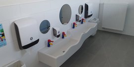 Ein modernes Badezimmer mit zwei Waschbecken, bunten Wasserhähnen und großen Spiegeln an der Wand.