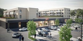 Ein modernes Gebäude mit einem Supermarkt im Erdgeschoss und mehreren Parkplätzen vor der Fassade ist zu sehen.
