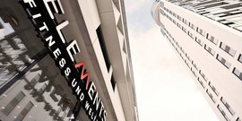 Das moderne Fitnessstudio-Logo 'ELEMENTS' ist prominent an der Wand eines eleganten Gebäudes angebracht.